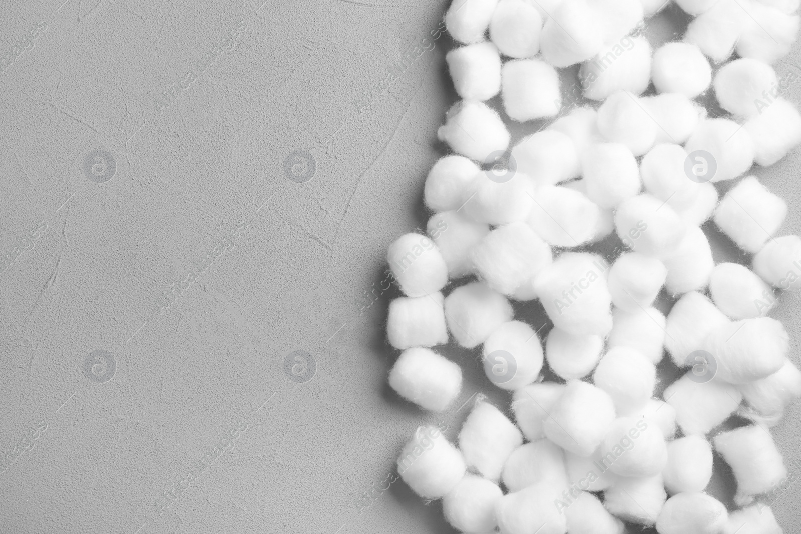 Photo of Many cotton balls and space for text on grey stone background, top view