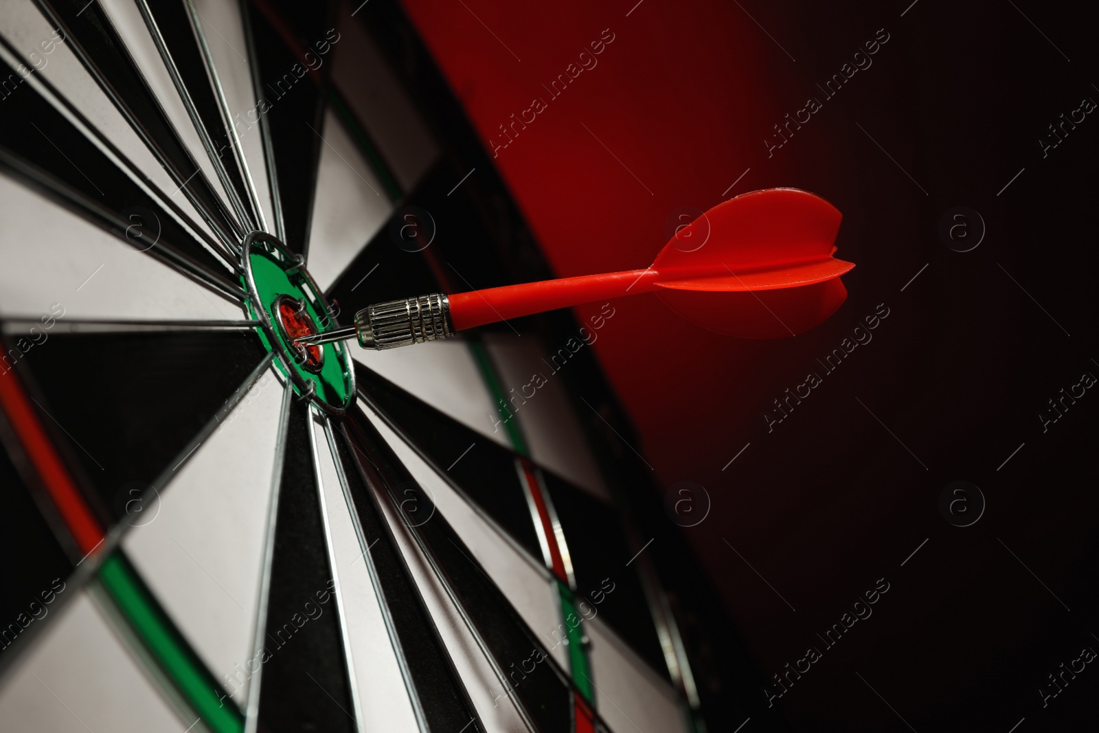 Photo of Color arrow hitting target on dart board against red background