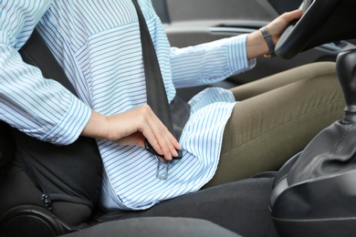 Photo of Female driver fastening safety belt in car, closeup