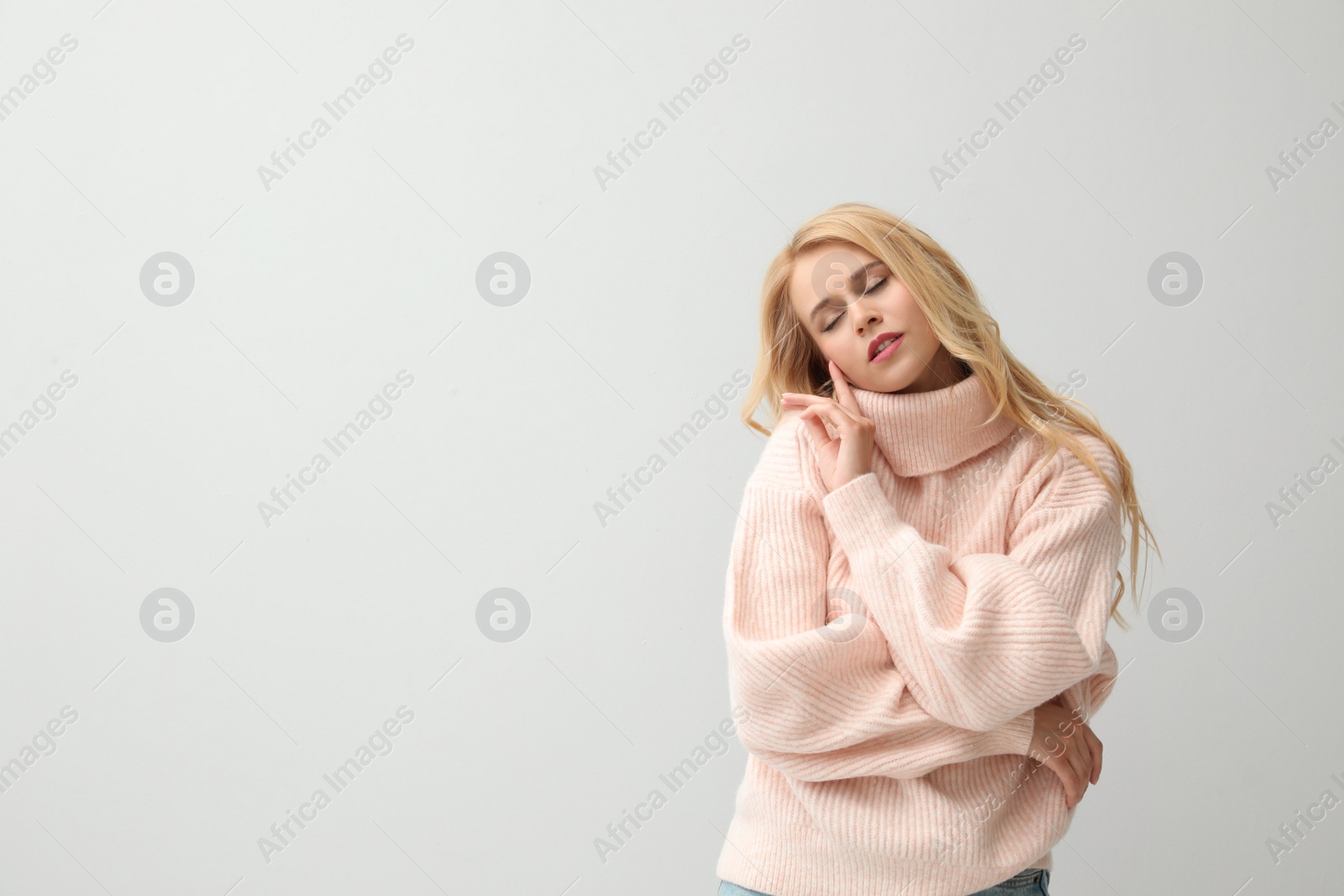 Photo of Beautiful young woman wearing warm pink sweater on white background. Space for text