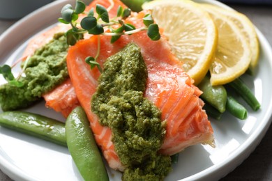 Tasty cooked salmon with pesto sauce on plate, closeup