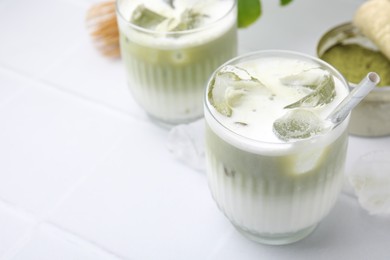 Photo of Glasses of tasty iced matcha latte on white table. Space for text