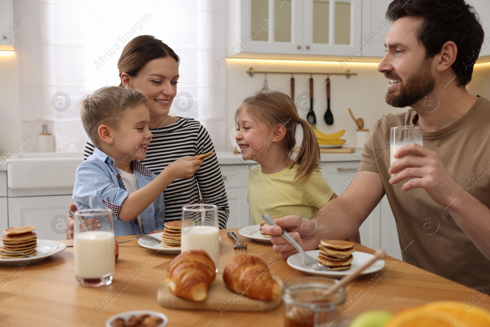 Photo of Happy family having fun during breakfast at table in kitchen