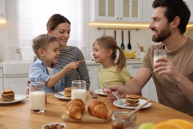 Photo of Happy family having fun during breakfast at table in kitchen