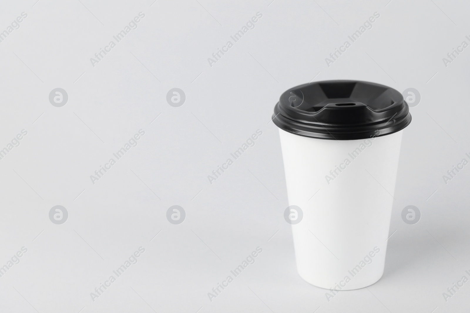 Photo of Paper cup with plastic lid on light background, space for text. Coffee to go