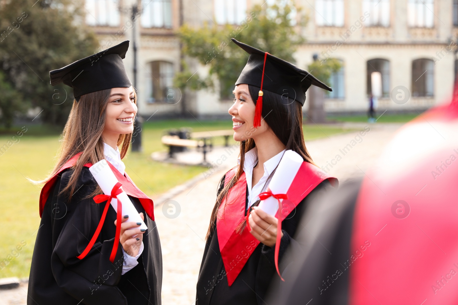 Photo of Happy students with diplomas outdoors. Graduation ceremony