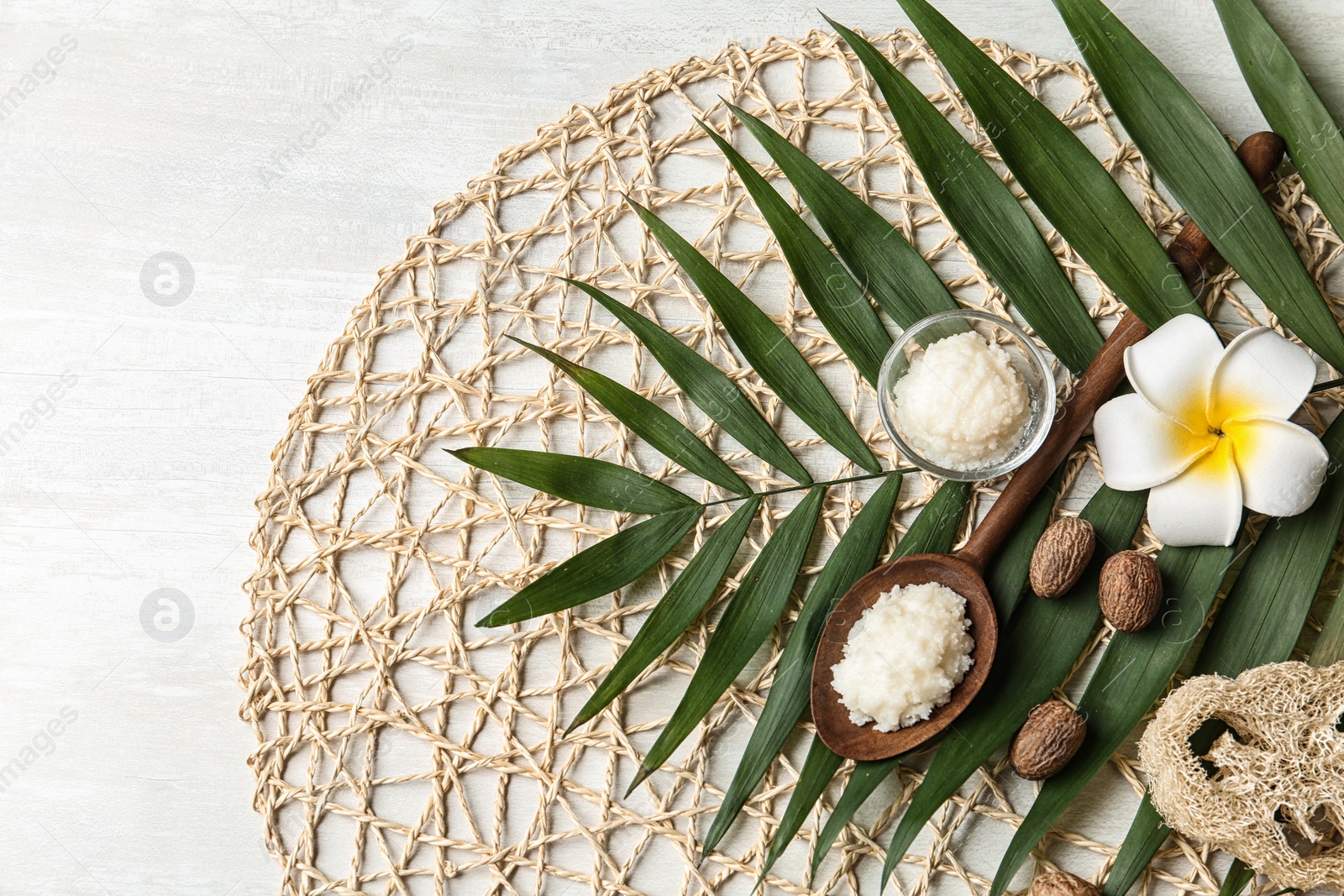 Photo of Flat lay composition with Shea butter, nuts and tropical leaf on light background. Space for text