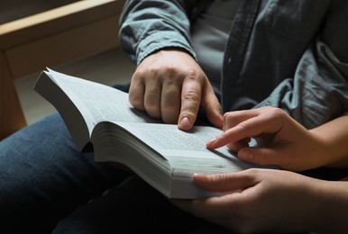 Couple sitting and reading holy Bible indoors, closeup