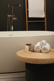 Spa day. Towels and candles on wicker table near tub in bathroom