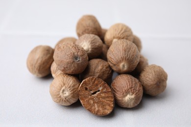 Heap of nutmegs on white table, closeup