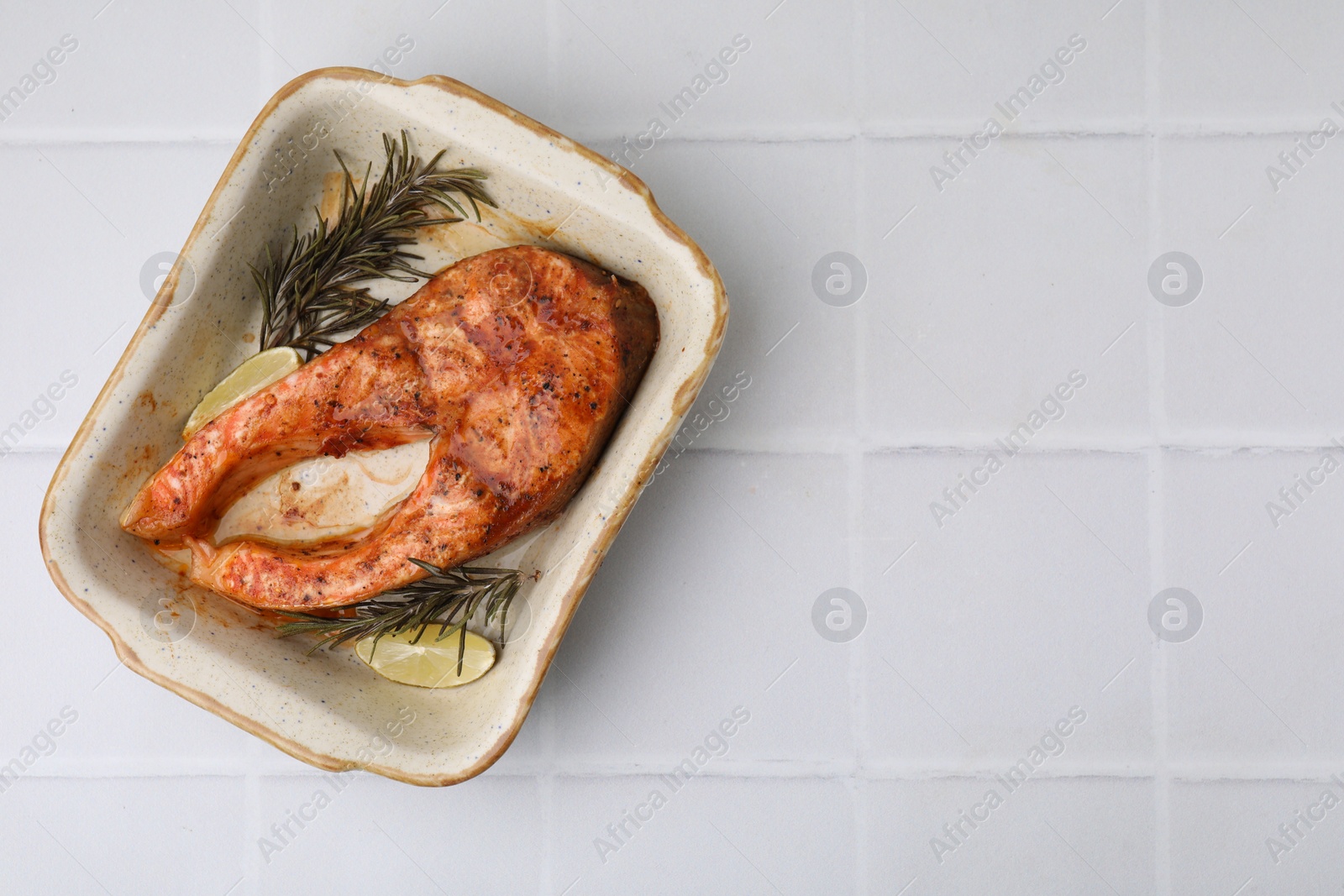 Photo of Freshly cooked fish, rosemary and lime on white tiled table, top view. Space for text