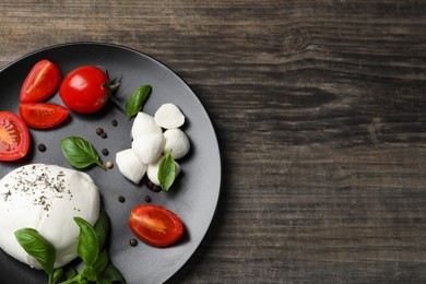 Photo of Delicious mozzarella with tomatoes and basil leaves on wooden table, top view. Space for text