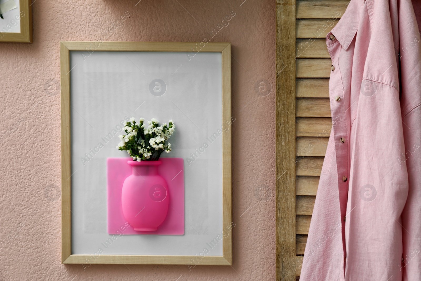 Photo of Silicone vase with beautiful white flowers on pink wall in room