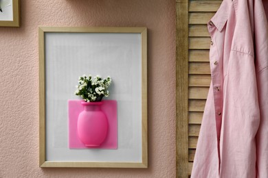 Silicone vase with beautiful white flowers on pink wall in room