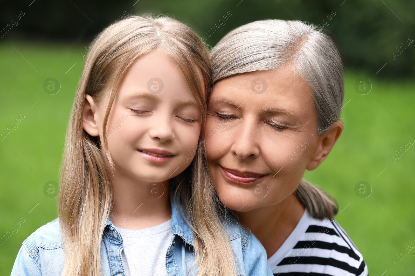 Photo of Portrait of happy grandmother with her granddaughter outdoors