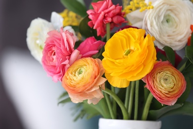 Photo of Vase with beautiful ranunculus flowers on blurred background