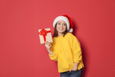 Young woman with Christmas gift on color background