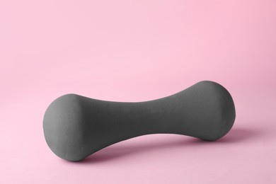 Photo of One grey dumbbell on light pink background
