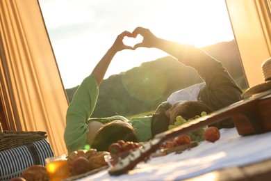 Photo of Romantic date. Couple making heart with hands during picnic on sunny day