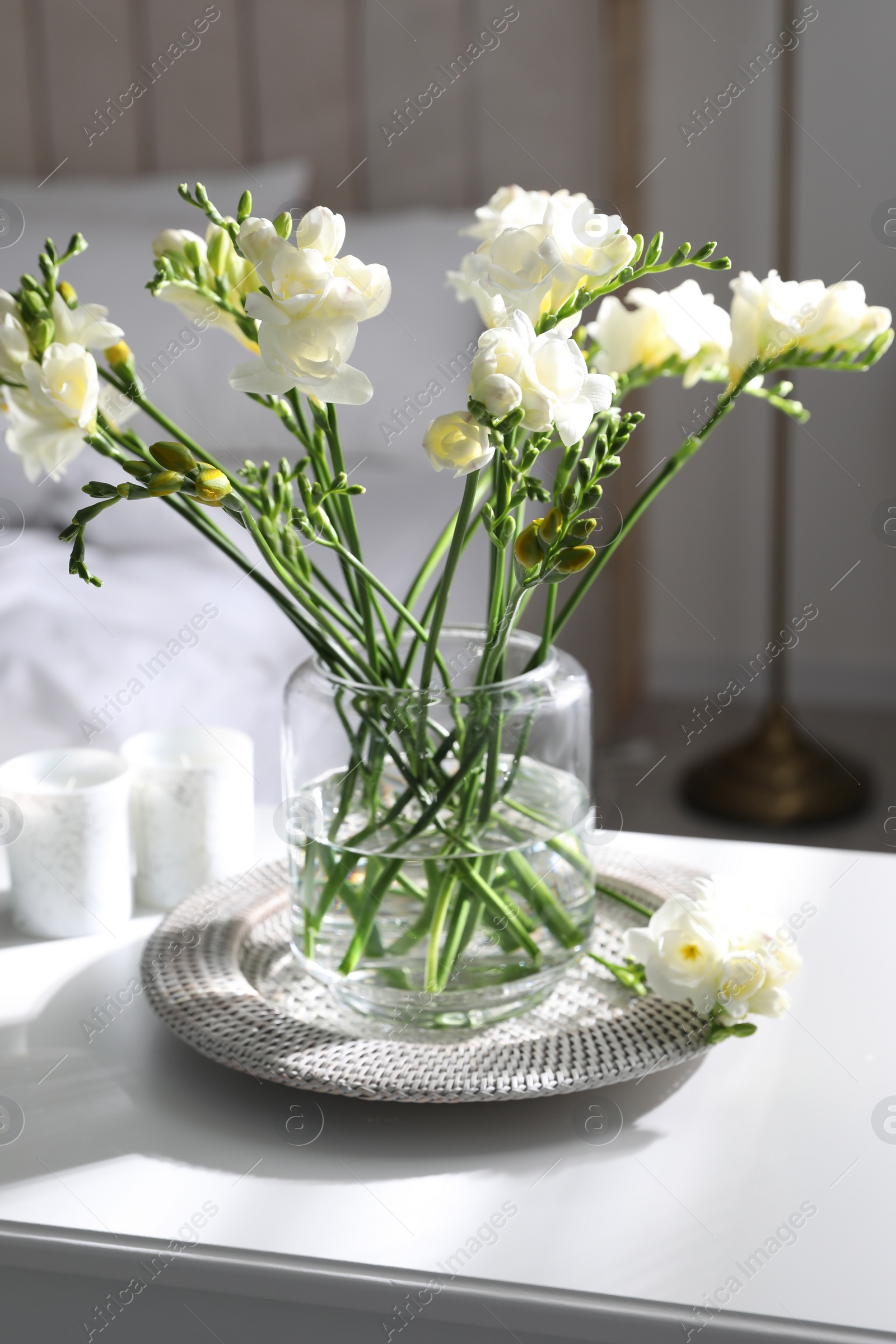 Photo of Beautiful spring freesia flowers on cabinet in bedroom