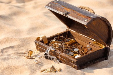 Open wooden treasure chest on sand, space for text
