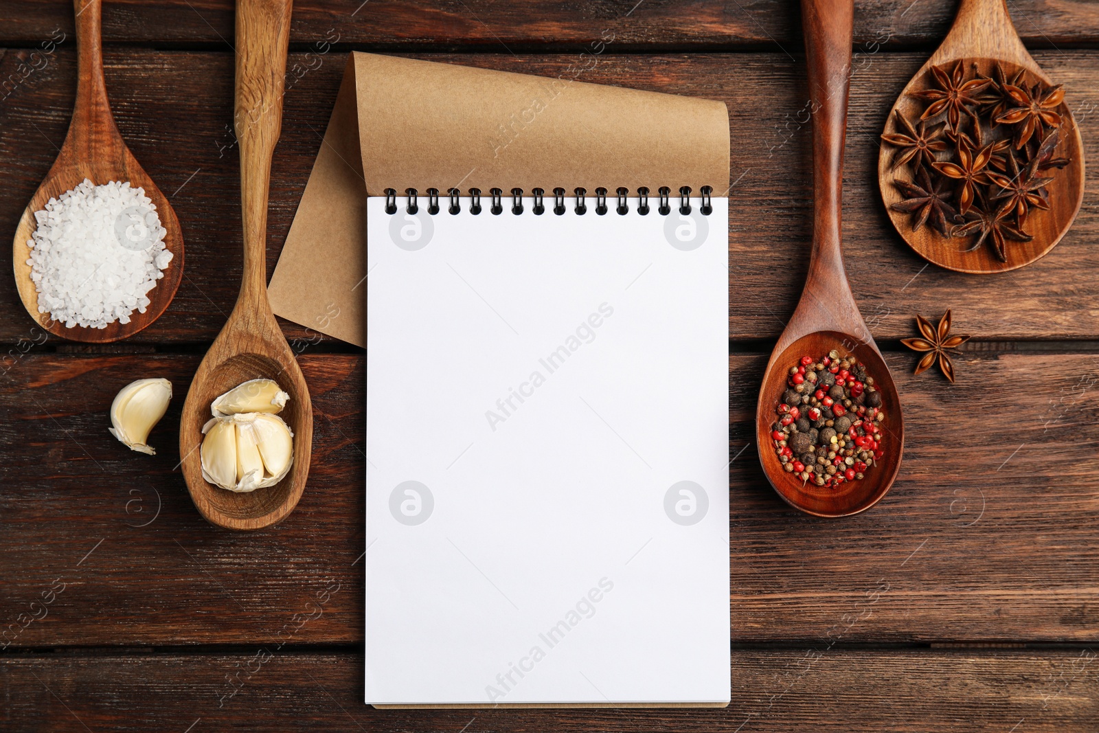 Photo of Notebook and different spices on wooden table, flat lay with space for text. Cooking Classes