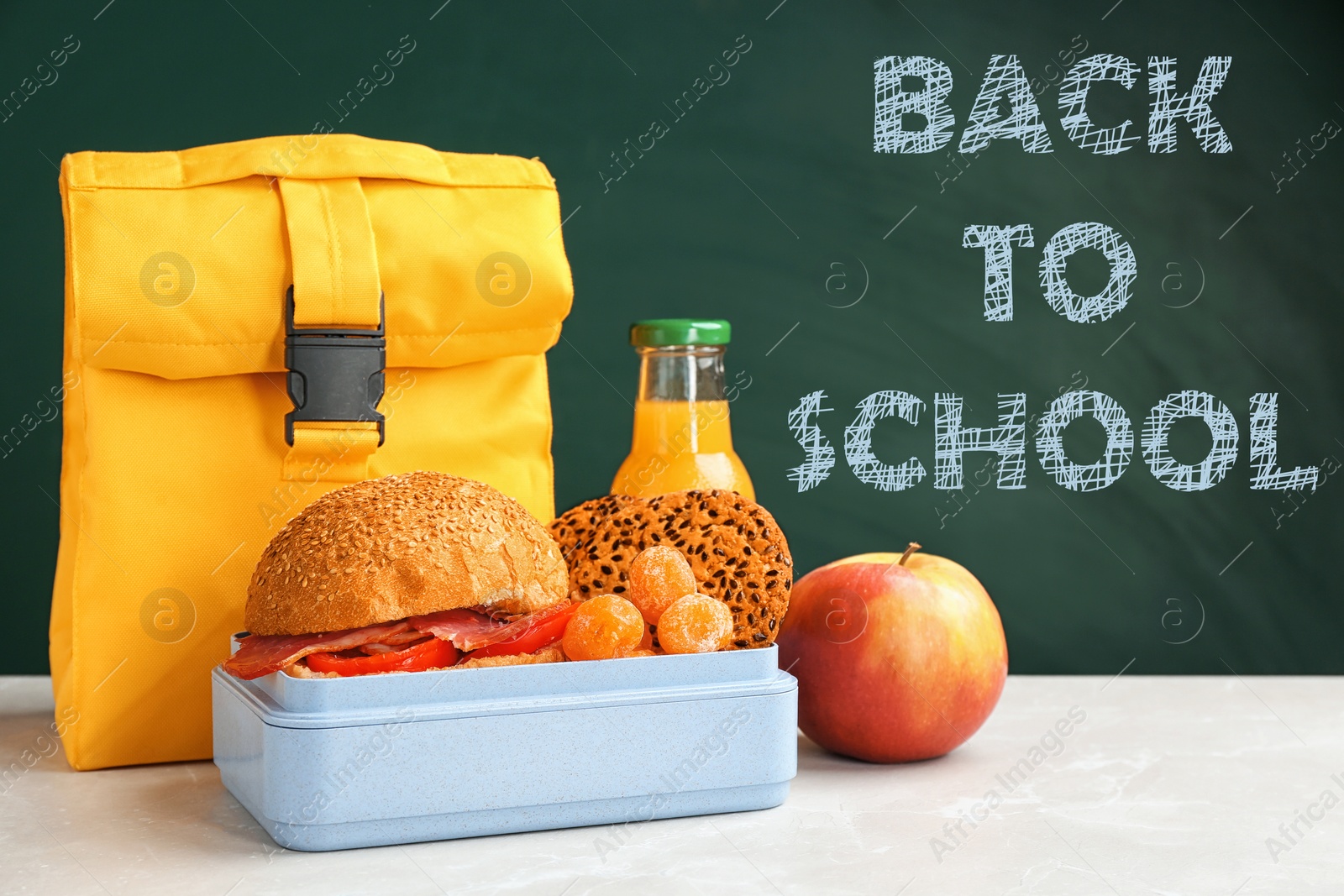 Image of Lunch box with appetizing food and bag on table near chalkboard