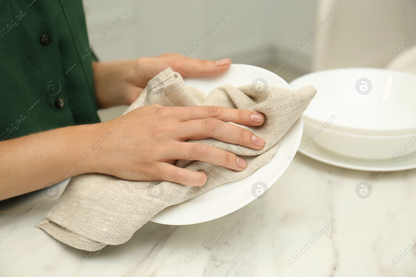 Photo of Woman wiping plate with towel in kitchen, closeup