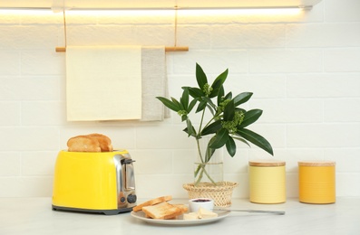 Modern toaster and tasty breakfast on counter in kitchen