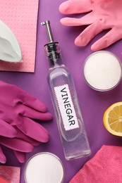 Photo of Eco friendly natural cleaners. Flat lay composition with bottle of vinegar and gloves on purple background