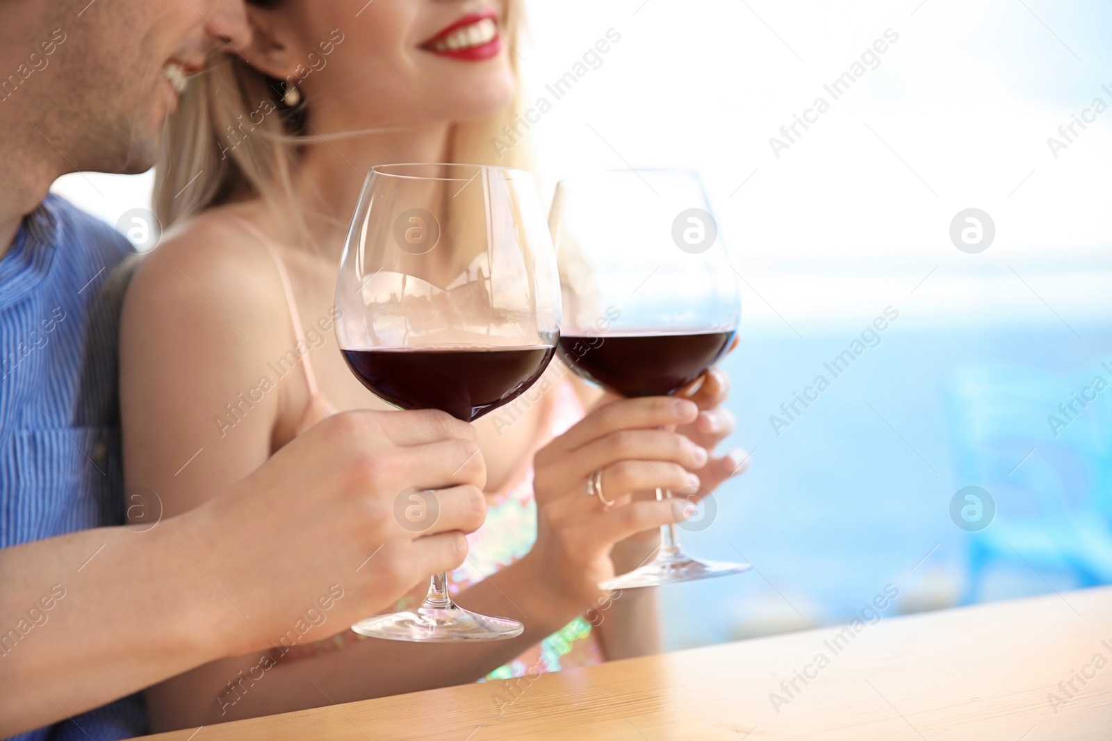 Photo of Young romantic couple with glasses of red wine at table