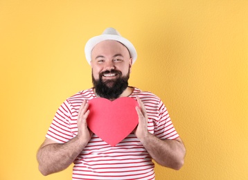 Emotional man with heart shaped box on color background