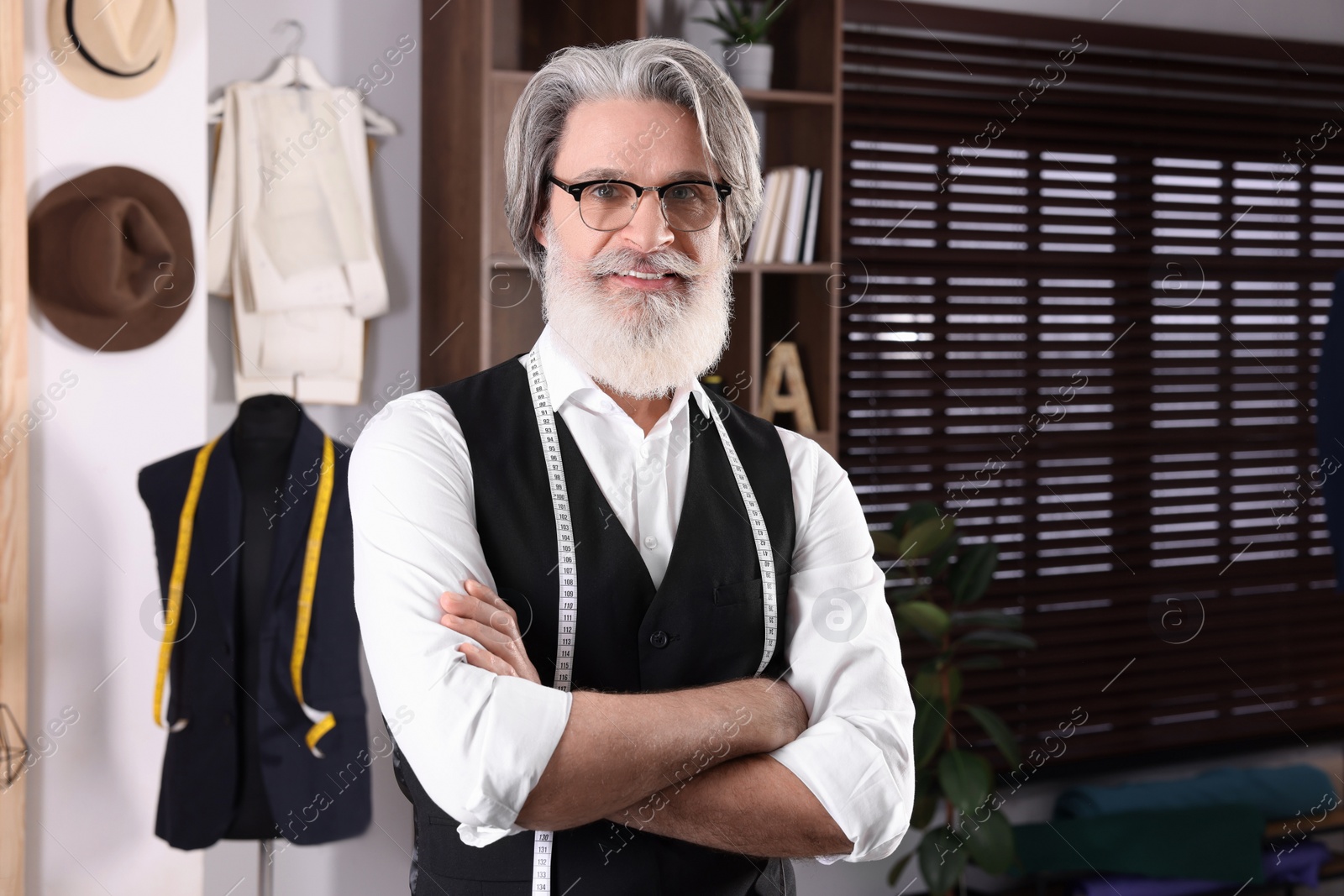 Photo of Professional tailor with measuring tape in workshop