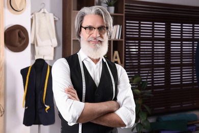 Professional tailor with measuring tape in workshop