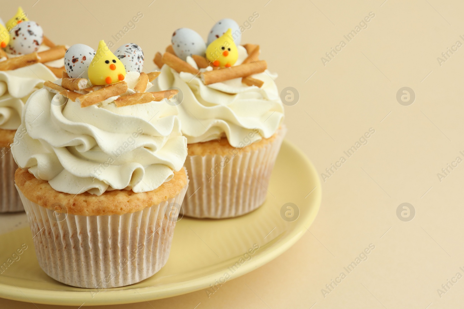 Photo of Tasty Easter cupcakes with vanilla cream on beige background, closeup. Space for text