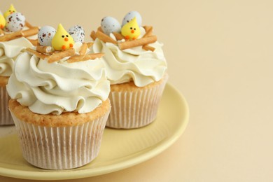 Photo of Tasty Easter cupcakes with vanilla cream on beige background, closeup. Space for text