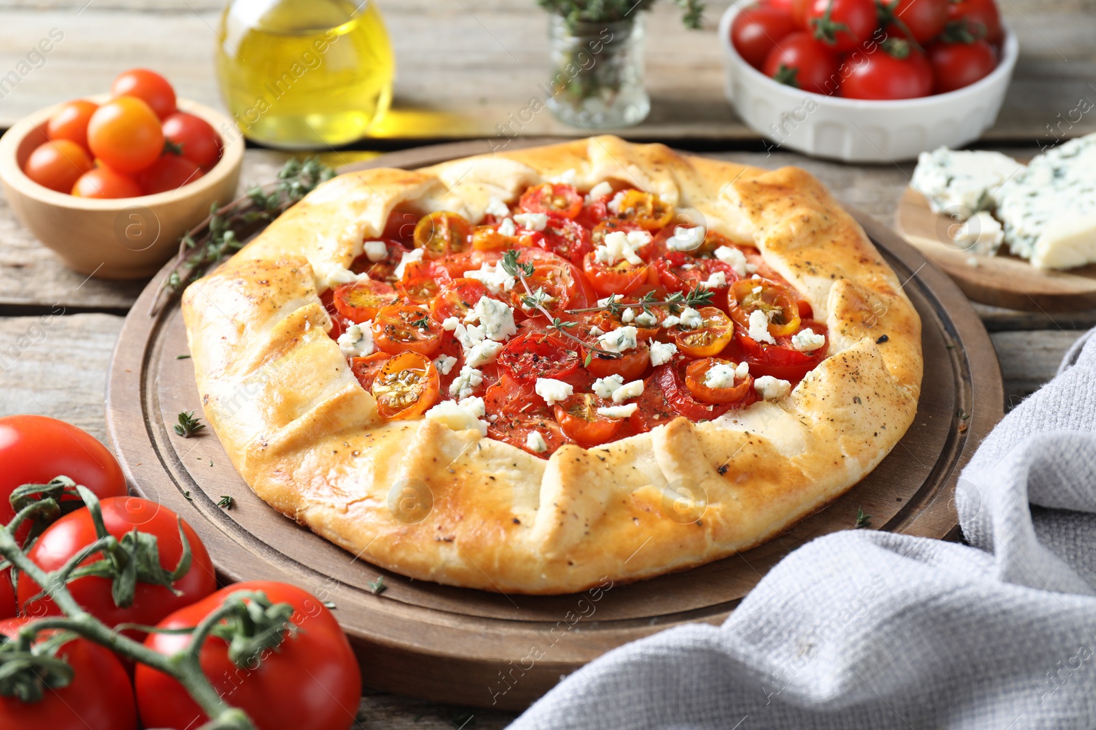 Photo of Tasty galette with tomato, thyme and cheese (Caprese galette) on wooden table, closeup