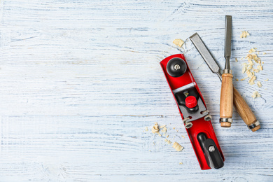 Modern carpenter's tools and shavings on white wooden background, flat lay. Space for text