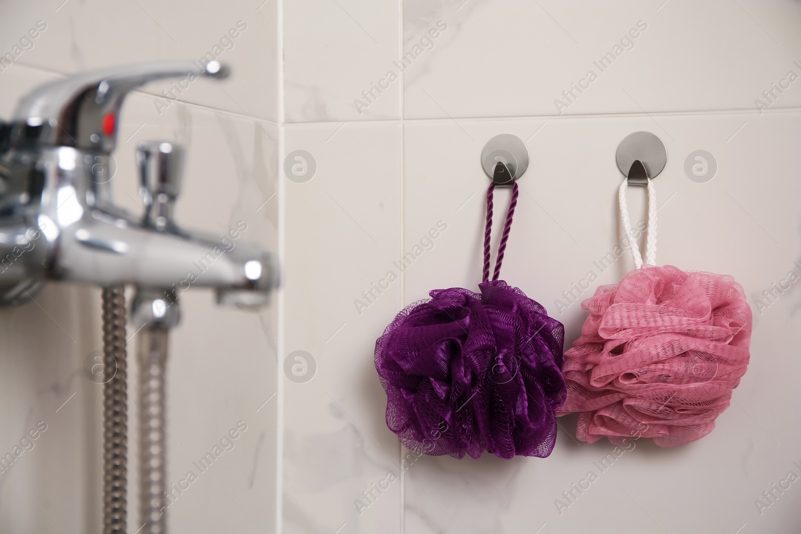 Photo of Shower puffs hanging near faucet in bathroom, space for text