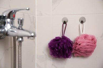 Shower puffs hanging near faucet in bathroom, space for text