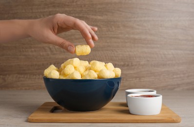 Photo of Woman taking corn sticks from bowl at wooden table, space for text