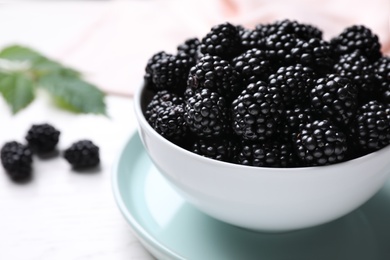 Photo of Fresh ripe blackberries in bowl on white table, closeup