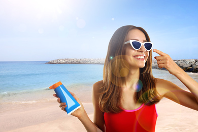 Image of Young woman applying sun protection cream at beach