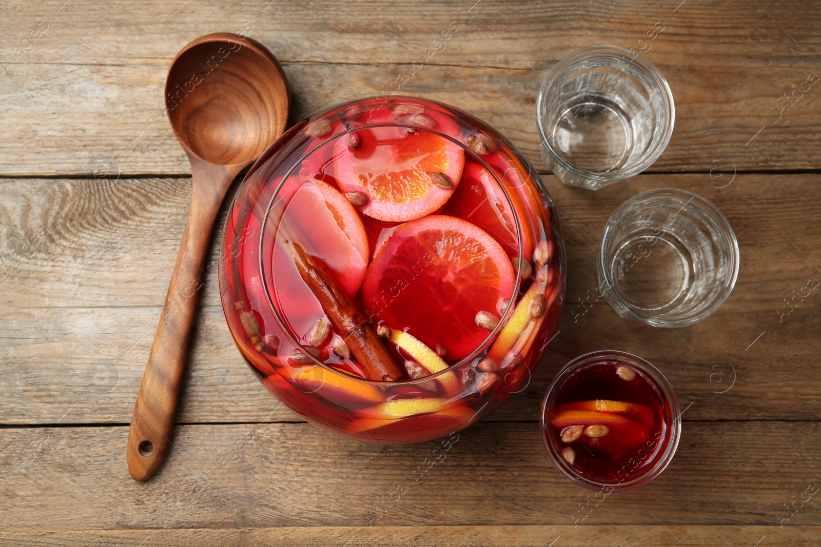 Photo of Aromatic punch drink with citrus fruits on wooden table, flat lay