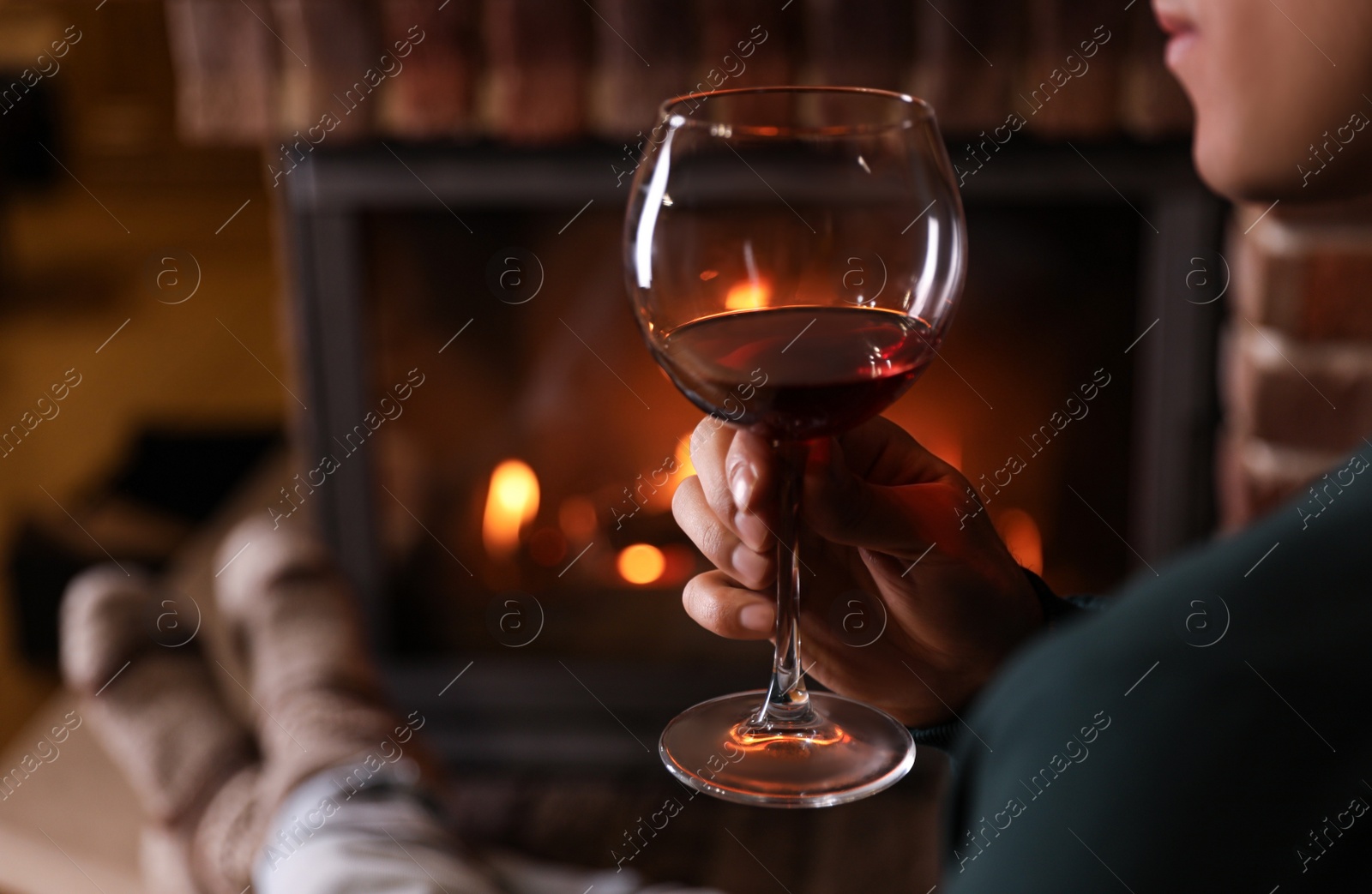 Photo of Man with glass of wine near fireplace at home, closeup