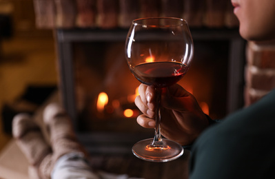 Photo of Man with glass of wine near fireplace at home, closeup