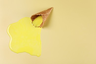 Photo of Melted ice cream and wafer cone on yellow background, top view. Space for text
