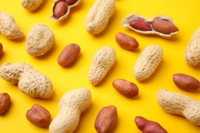 Photo of Fresh peanuts on yellow table, above view