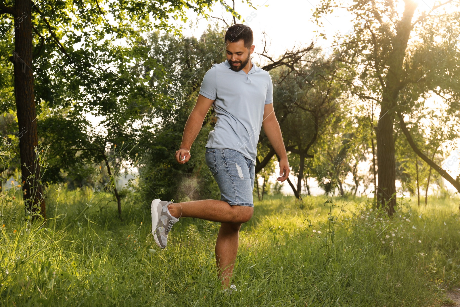 Photo of Man applying insect repellent on leg in park. Tick bites prevention