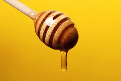 Pouring honey from dipper against golden background, closeup. Space for text